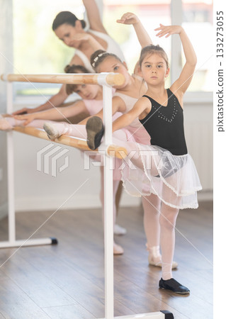 Little ballerinas together with choreography teacher in grand batman pose learn to dance ballet Little ballerinas together with choreography teacher in grand batman pose learn to dance ballet 133273055