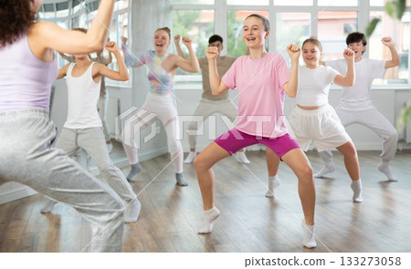 Female teacher performs choreographic exercises and teaches energetic mobile house dance together with teenagers 133273058