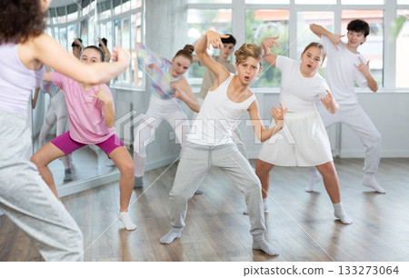 Young girls and boys repeat the movements of dance teacher, training in spacious studio Young girls and boys repeat the movements of dance teacher, training in spacious studio 133273064
