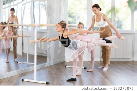 Woman teacher corrects girls in arabesque movement Woman teacher corrects girls in arabesque movement 133273075
