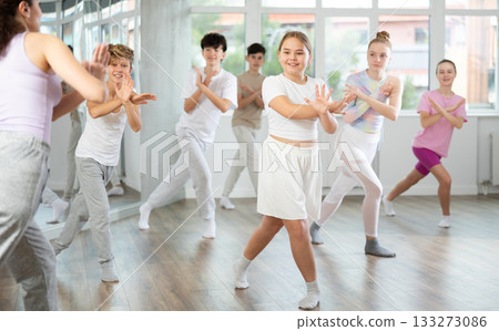 Young girls and boys repeat the movements of dance teacher, training in spacious studio 133273086