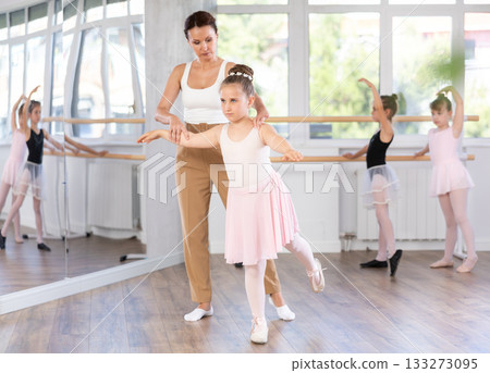 Woman teacher corrects movement of girl dancer Woman teacher corrects movement of girl dancer 133273095