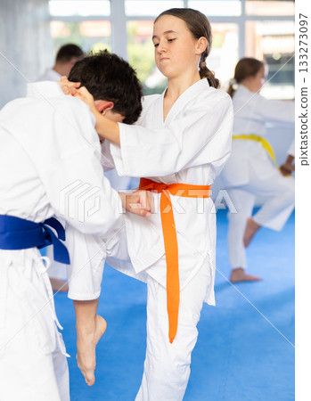 Karate training - girl and boy of different nationalities in pairs exercising karate movements during group training in gym Karate training - girl and boy of different nationalities in pairs exercising karate movements during group training in gym 133273097