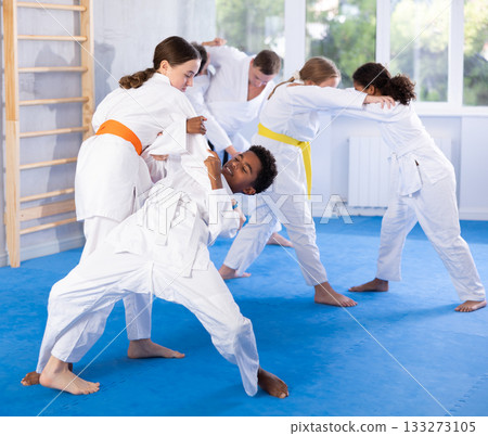 Teenage girl practicing fighting techniques during martial arts sparring with boy 133273105