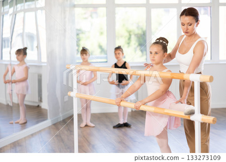 Ballet pose grand batman - little girls at a choreography lesson are learning ballet movements in studio Ballet pose grand batman - little girls at a choreography lesson are learning ballet movements in studio 133273109