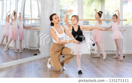 In studio, mentor corrects girls arm and leg, teaches correct dynamics and execution of movements 133273111