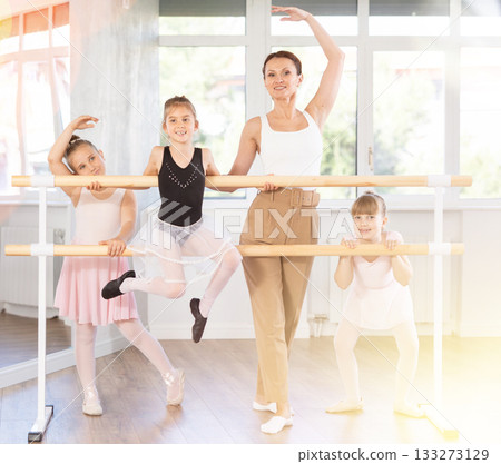 Woman teacher and group of girls posing at barre 133273129