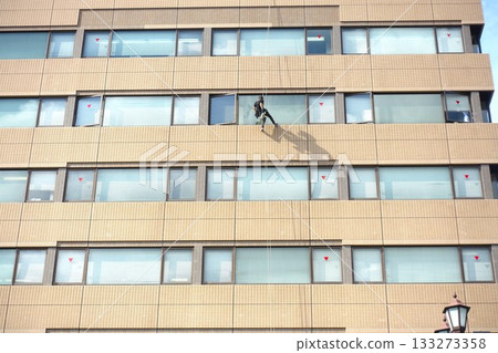 Workers cleaning windows in a high-rise building 133273358