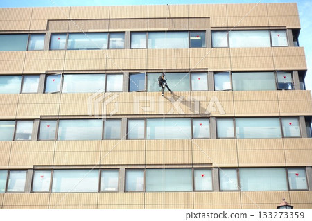 Workers cleaning windows in a high-rise building 133273359