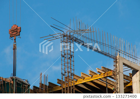 Red Rusty Hook suspension of Tower Crane nearby Connected Fittings with formwork and racks on Blue Sky background in clear weather at Construction Site for Lifting and Moving Goods 133273400