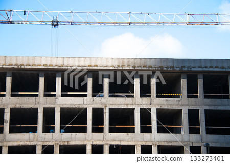 Front view Concrete Wall Frame of Building under Construction with Tower Crane Boom. Formwork Prints with wooden Fence. Monolithic box window holes Construction Site. Architectural origin Structure. 133273401