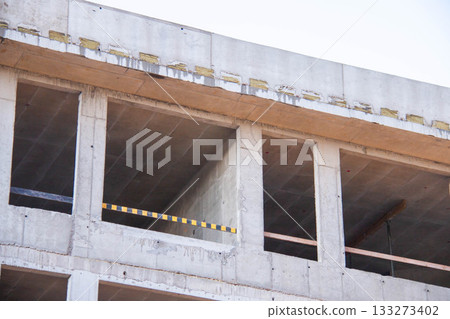 Concrete Wall Frame of Building under Construction. Formwork Prints Surface with Thermal Pads, black-yellow Fence. Monolithic box with window holes Construction Site. Architectural origin Structure. 133273402