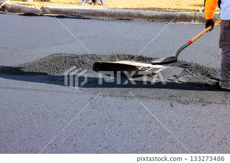 Road repair crew patching pothole in residential area 133273486