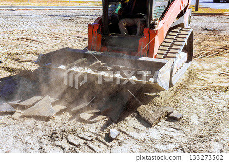 Construction equipment levels ground while removing debris in an outdoor worksite Construction equipment levels ground while removing debris in an outdoor worksite 133273502