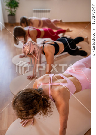 Three women are practicing downward dog variations emphasizing focus and balance in energetic Three women are practicing downward dog variations emphasizing focus and balance in energetic 133273547