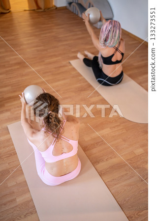 Women exercise unity, team workout with stability balls, women synchronize core exercises in studio 133273551