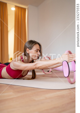 Exercises with pilates ring. Woman doing aerobics workout at pilates studio with panoramic windows. 133273553