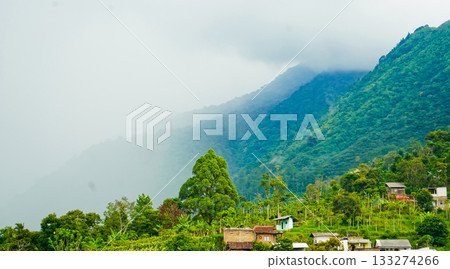 beautiful view of a village at the foot of a hill covered in mist 133274266