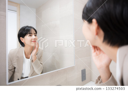 A woman checking her makeup and appearance in the mirror 133274503