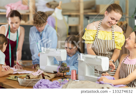 Teenage girl chatting with classmate during sewing lesson Teenage girl chatting with classmate during sewing lesson 133274632