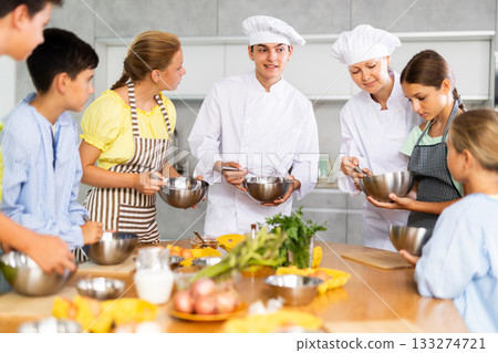 Amiable male and female chefs in white uniform running culinary courses for children Amiable male and female chefs in white uniform running culinary courses for children 133274721