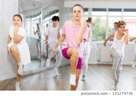 Woman teacher in background dances with students, inspects and observes skill of dancers Woman teacher in background dances with students, inspects and observes skill of dancers 133274736