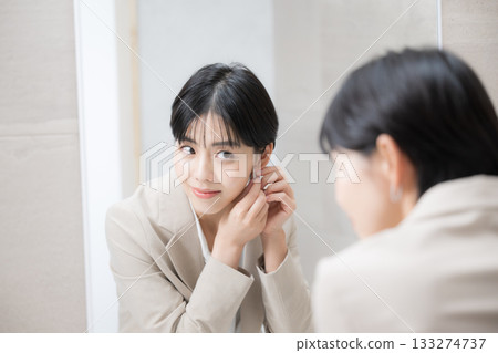 一位女士對著鏡子微笑,整理儀容,穿著飾品,展現了她美麗的一面。 一位女士對著鏡子微笑,整理儀容,穿著飾品,展現了她美麗的一面。 133274737