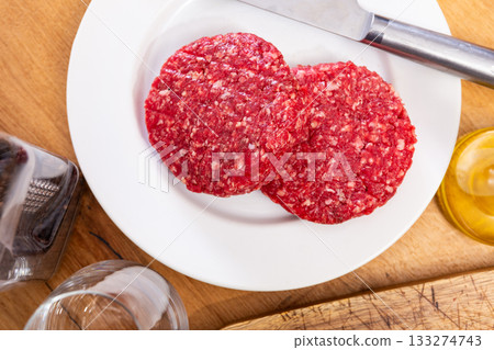 Two raw juicy beef burger cutlets are prepared for frying 133274743