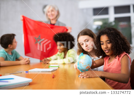 Female teacher showing moroccan flag to kids in geography class 133274772