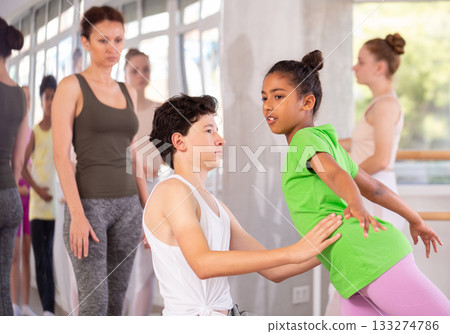 Teenage girl practicing ballet positions in pair with boy in dance studio 133274786