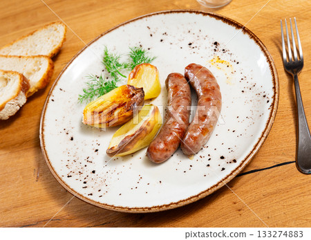 Cooked sausages with potatoes on a plate 133274883