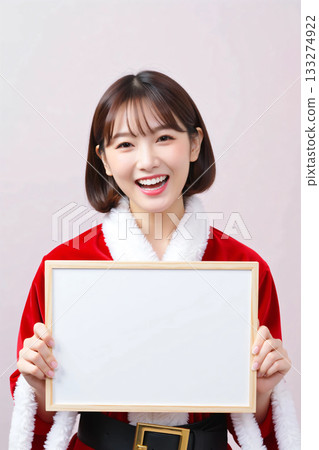 A woman in Santa costume holding a white board 133274922