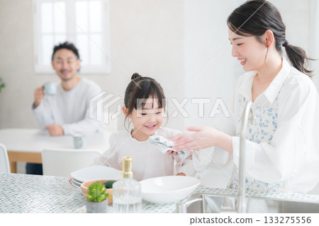 A smiling family life scene with parents and children washing dishes in a bright kitchen A smiling family life scene with parents and children washing dishes in a bright kitchen 133275556