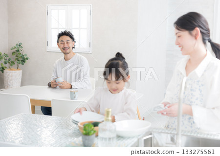 A smiling family life scene with parents and children washing dishes in a bright kitchen 133275561