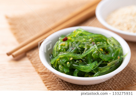 Wakame seaweed salad with sesame seed in a bowl on wooden background Wakame seaweed salad with sesame seed in a bowl on wooden background 133275931