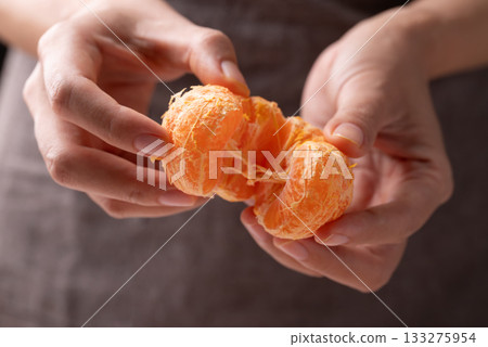 Mandarin orange fruit holding by hand and eating 133275954