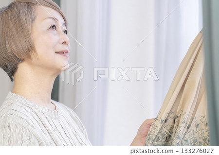 Senior woman holding a parasol in summer Senior woman holding a parasol in summer 133276027
