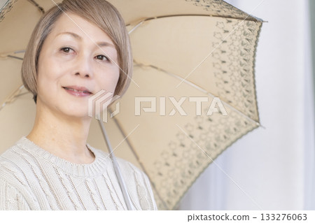 Senior woman holding a parasol in summer Senior woman holding a parasol in summer 133276063