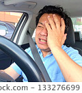 A middle-aged driver covers his face after crashing his car 133276699