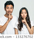 A young couple posing secretly with their index fingers on their lips 133276702
