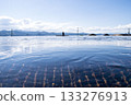 A tranquil, breathtaking landscape of the sky and mountains reflected on the water, with a silhouetted figure standing there 133276913