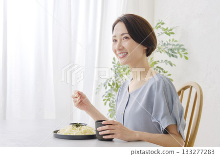 一位女士在客廳吃笊籬烏龍麵 133277283