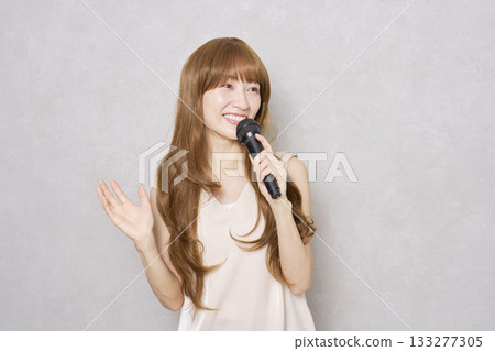 中年婦女手持麥克風唱歌，肖像，灰色背景 133277305
