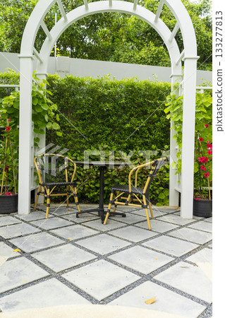 Wooden chairs and table in a beautiful garden canopy in home landscaped garden in summer. Wooden chairs and table in a beautiful garden canopy in home landscaped garden in summer. 133277813
