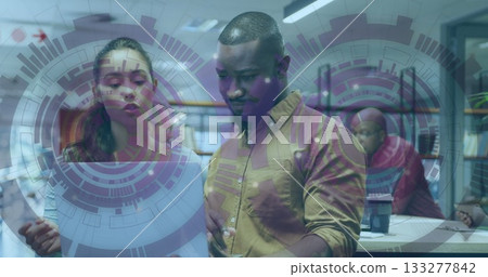 Woman and man coworkers examining document at wooden desk in open-plan office, with digital overlay 133277842