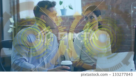 Colleagues talking at desk in office, with open laptop disposable coffee cup whiteboard plant Colleagues talking at desk in office, with open laptop disposable coffee cup whiteboard plant 133277843