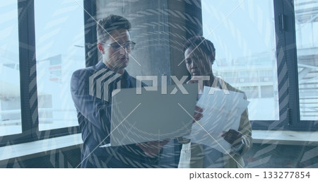 Pointing at laptop screen and reviewing printed documents with pen by large glass window at airport Pointing at laptop screen and reviewing printed documents with pen by large glass window at airport 133277854