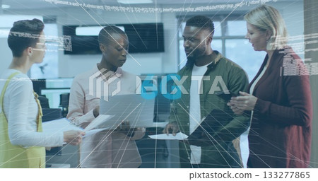 Collaborating four professionals discussing connectivity in office, with silver laptop and paper 133277865