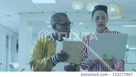 Pointing at tablet screen man in jacket showing woman in striped blouse in office, with laptop 133277987