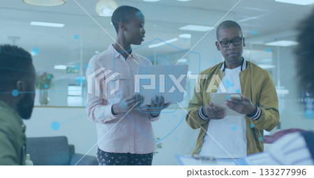 Presenting team in casual attire reviewing data in open plan office, with laptop tablet graphics Presenting team in casual attire reviewing data in open plan office, with laptop tablet graphics 133277996